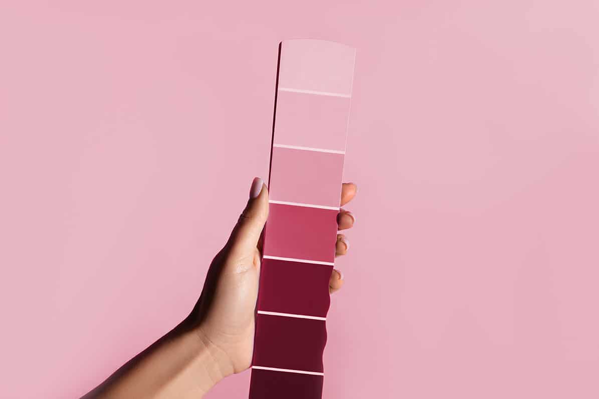 Hand holding a pink pontone colour gradient strip against a pink background