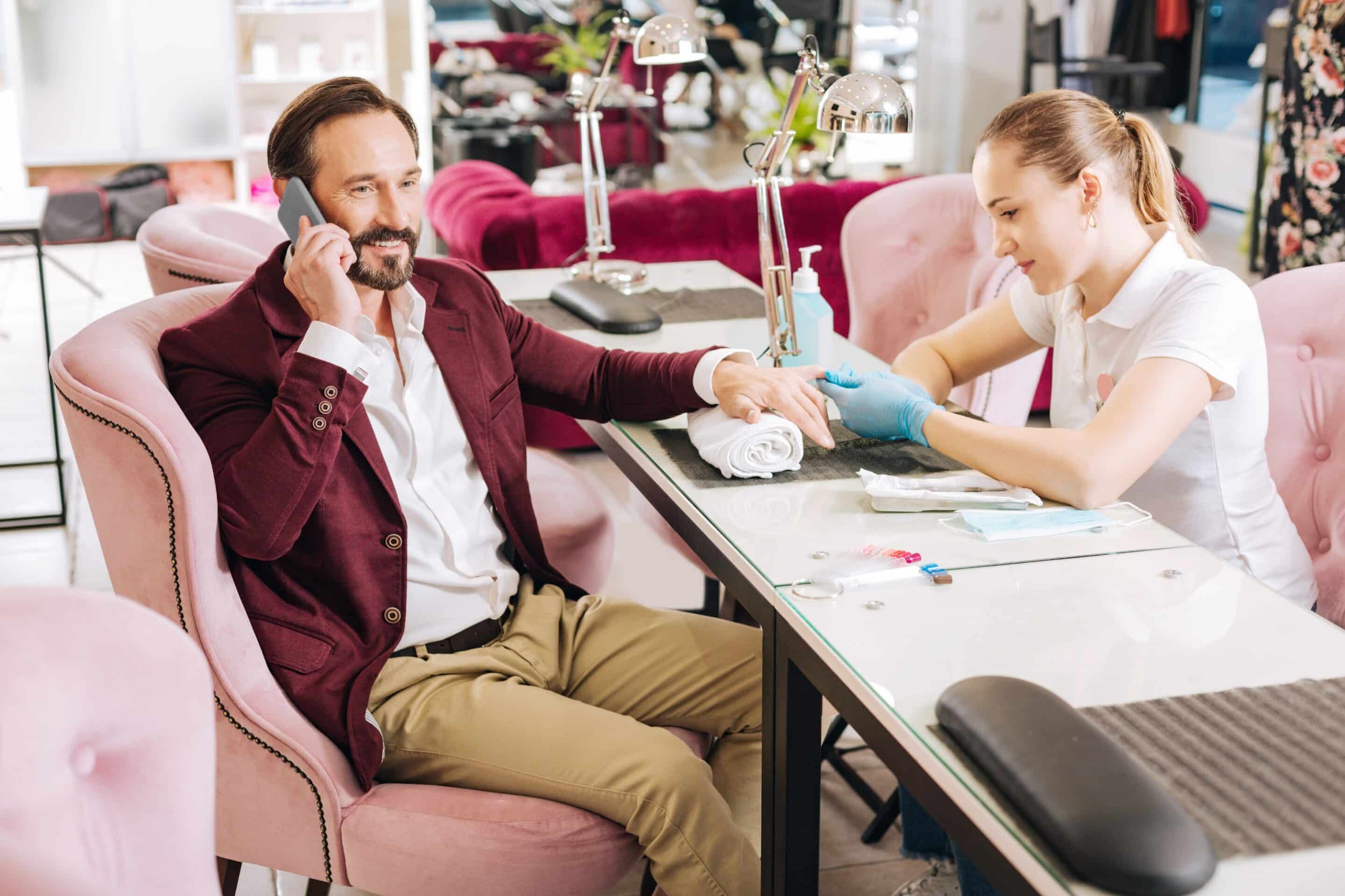 Man receiving manicure in salon.